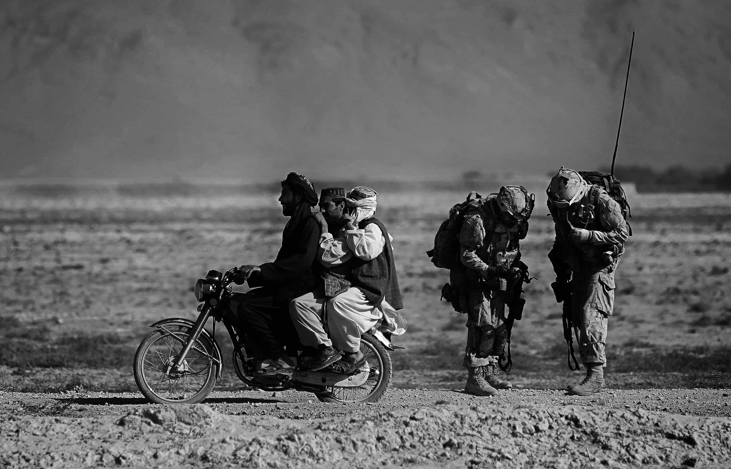 Anja Niedringhaus, Afghan men on a motorcycle overtake Canadian soldiers with the Royal Canadian Regiment during a patrol in the Panjwaii district, southwest of Kandahar, Salavat, Afghanistan, September 2010. © picture alliance / AP Images 