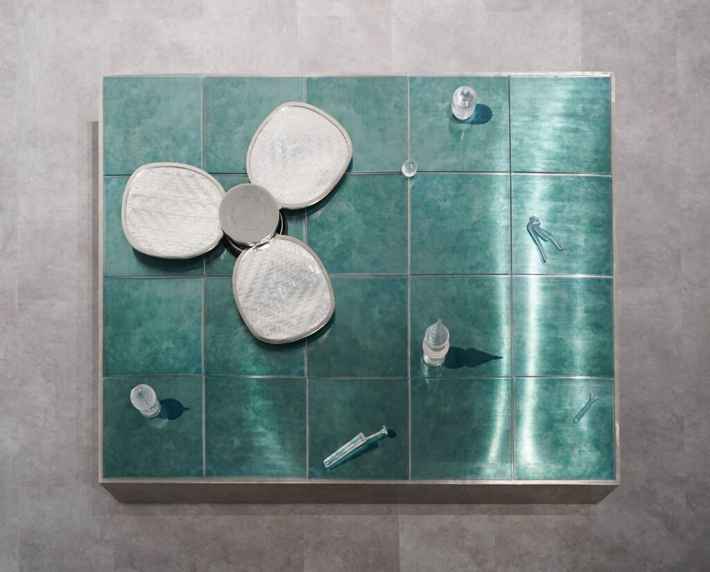 Natalie Sasi Organ, I learned fire at her knee, 2026, metal platform, UV print perspex. resin, kinetic stainless steel fan, 42 x 123 x 153 cm. Courtesy of the artist